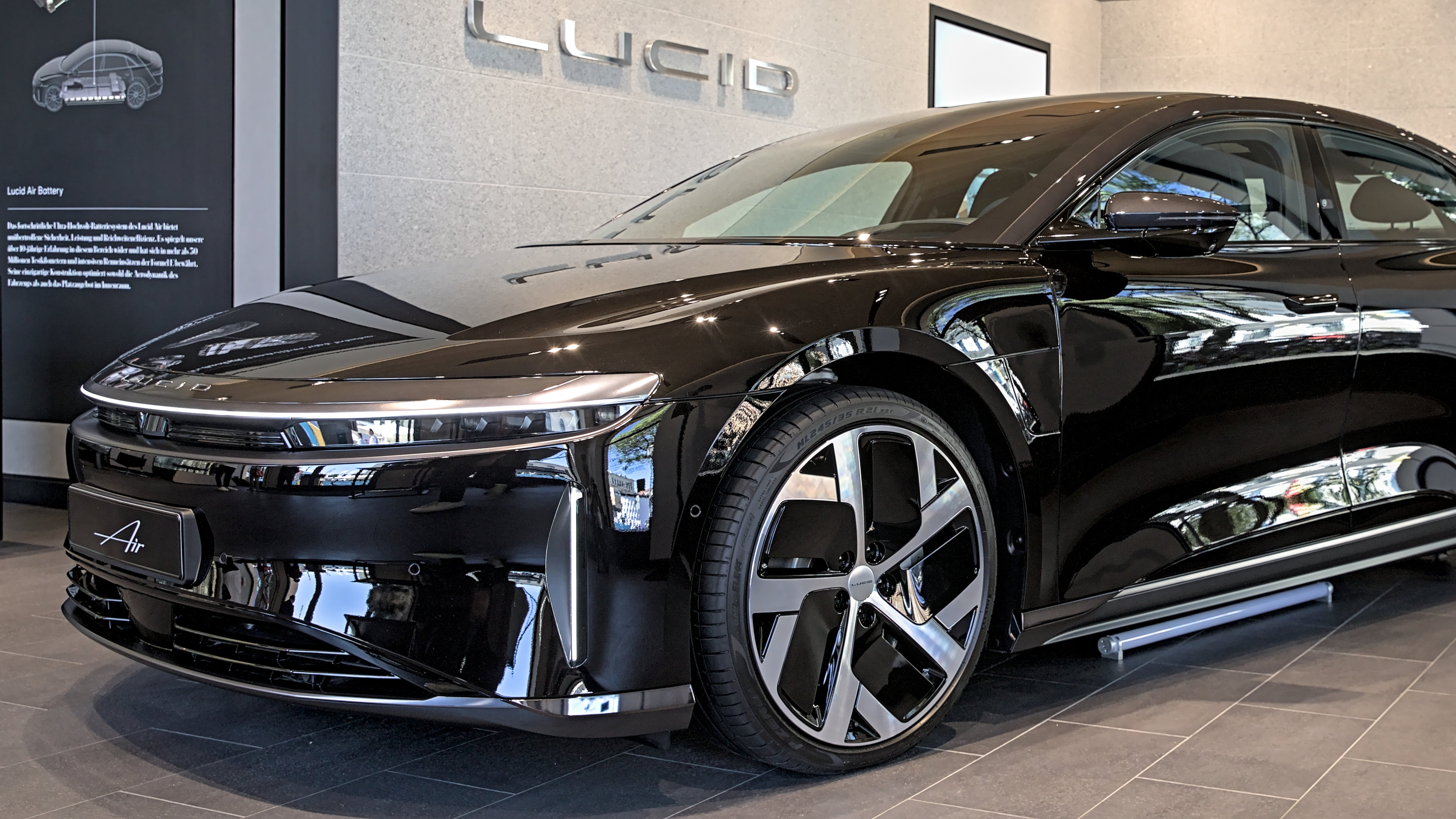 Lucid AIr at IAA 2023. The image shows a black, shiny vehicle in front of a wall emblazoned with the Lucid logo.