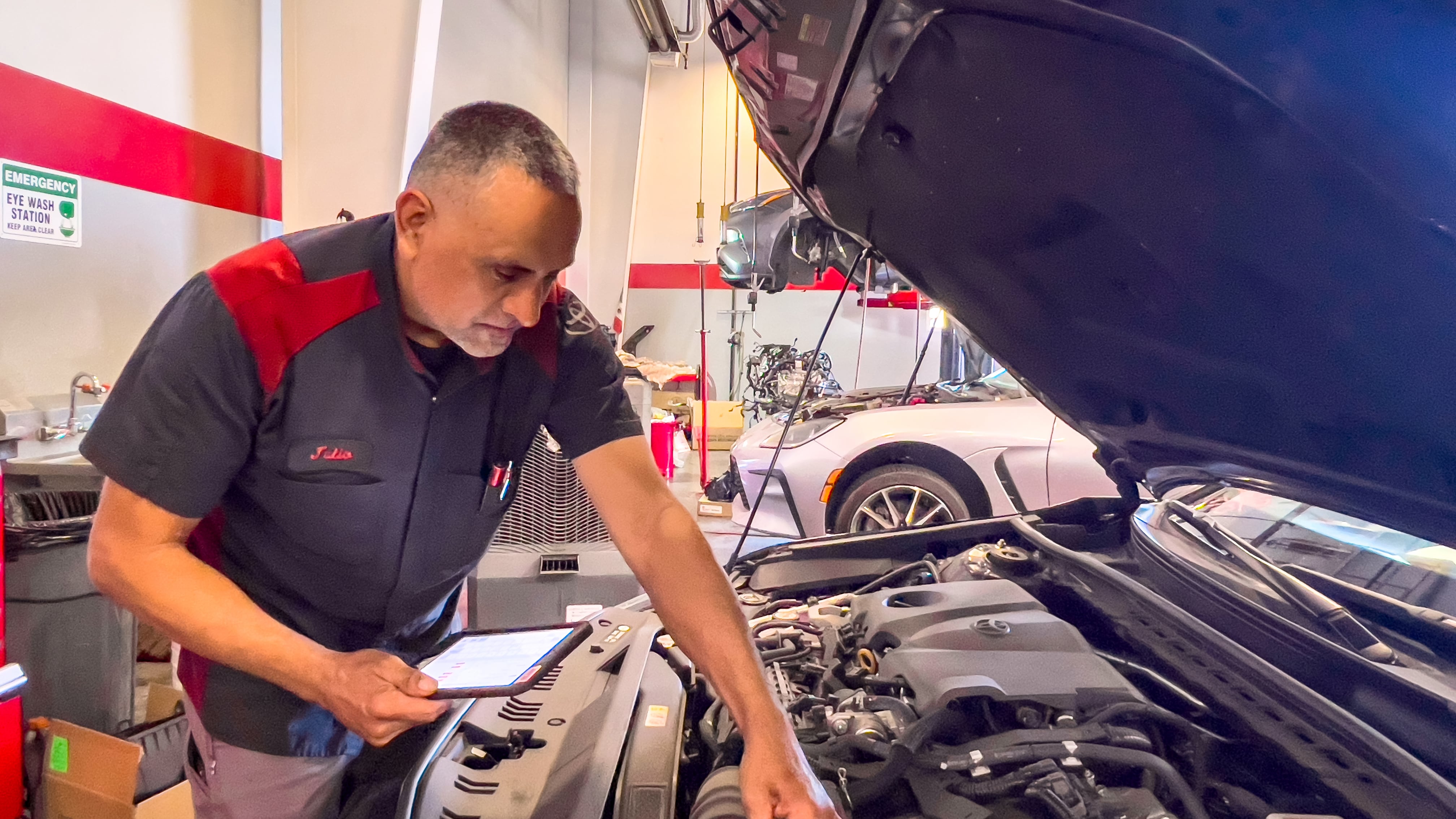 Julio Ochoa, a certified Toyota technician, uses a handheld tablet equipped with techWALL software while performing a multipoint inspection of a vehicle at Toyota of Selma in California.